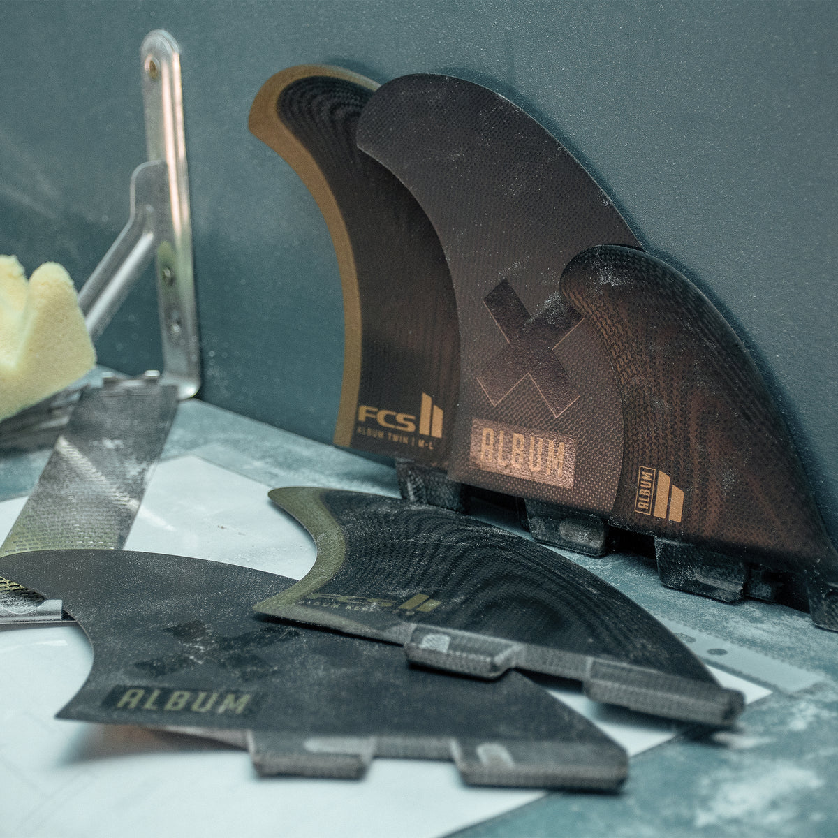 FCS II Album Keel Twin Fin Set - Performance Glass: album fins on a shaping workshop table