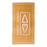 Ocean & Earth Priority Beach Towel: Gold logo beach towel laid flat