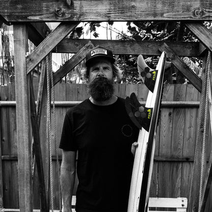 FCS II Al Merrick PG Pro Tri Fin Set - Performance Glass: black and White portrait of Al Merrick with a surfboard