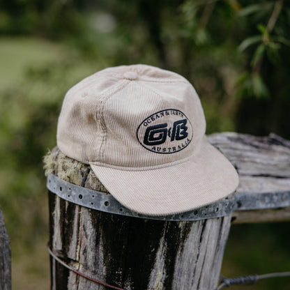 Ocean & Earth Heritage Cap: Almond cap resting on a post