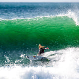 FCS Caroline Marks Traction: caroline Marks riding a wave beneath a green breaking lip