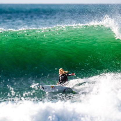 FCS Caroline Marks Traction: caroline Marks riding a wave beneath a green breaking lip
