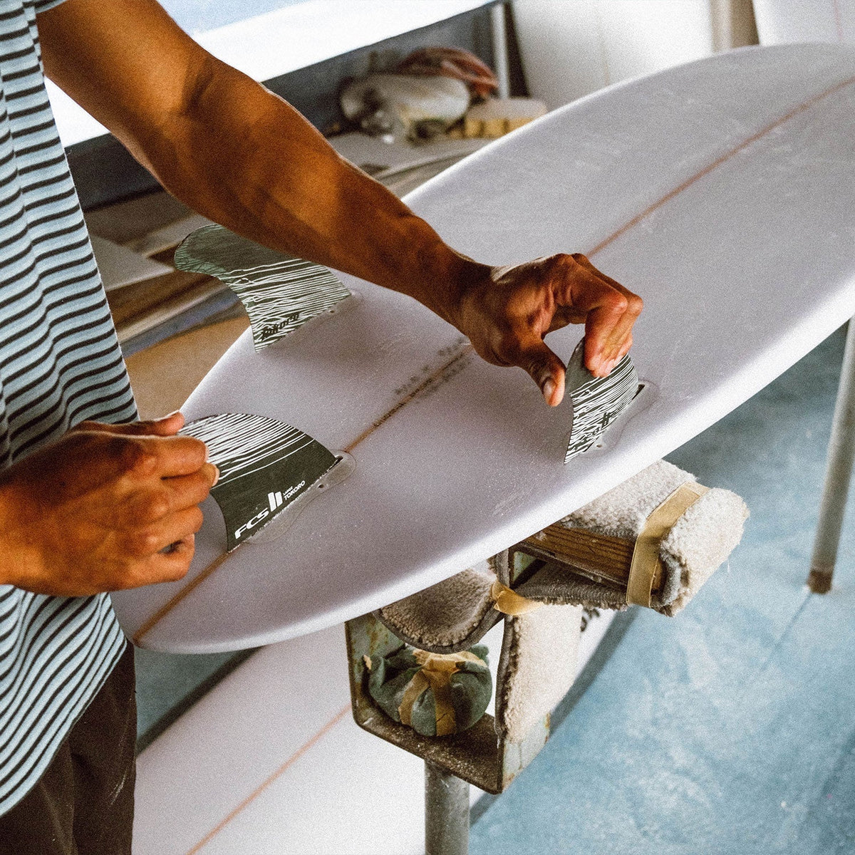 FCS II Tokoro Tri Fins - Performance Core: shaper working on the underside of a board