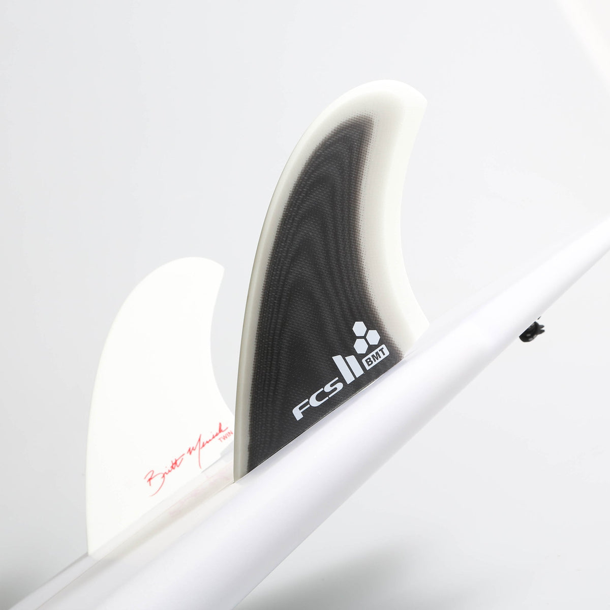 Black and white Britt Merrick twin fins mounted on a white surfboard