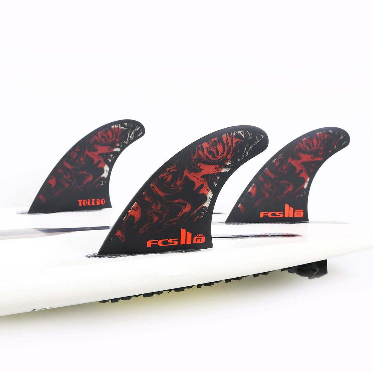 Filipe Toledo black and red thruster set mounted on a white surfboard in the studio