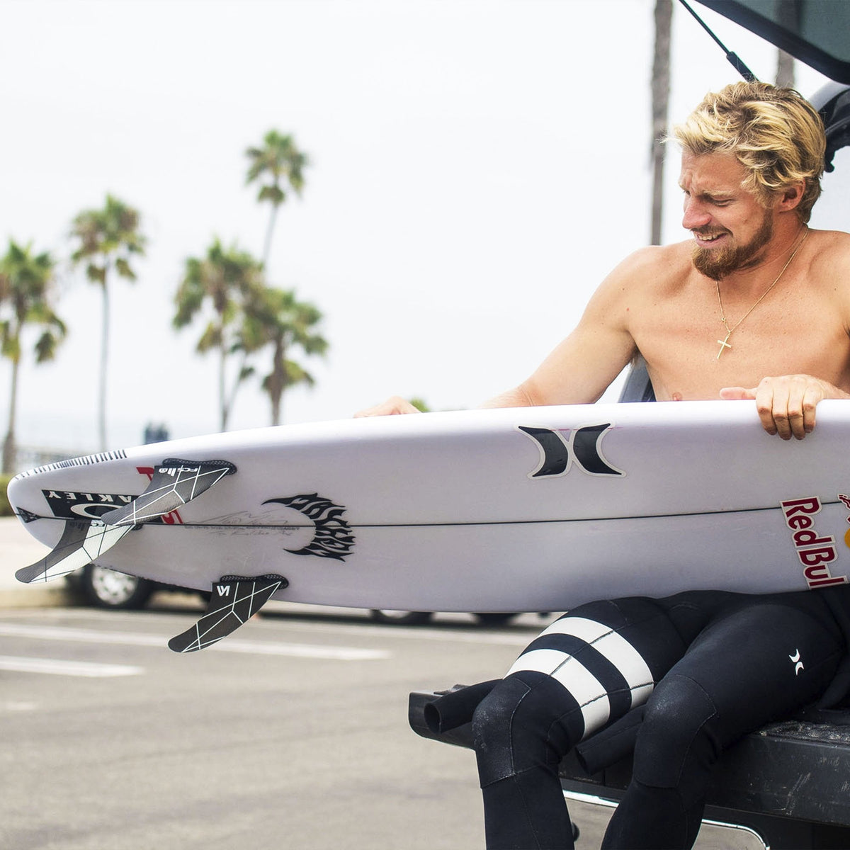 FCS II Kolohe Andino Tri Fins - Performance Core: kolohe Andino holding a surfboard on a coastal promenade
