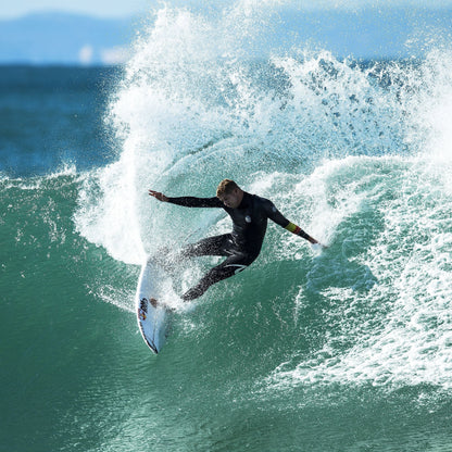 FCS II Mick Fanning Tri Fins - Performance Core: mick Fanning carving a green wave with spray behind him