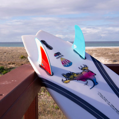 Freeride twin fins mounted on a white surfboard beside a coastal railing