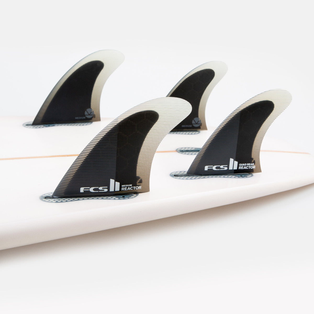 FCS II Reactor Quad Rear Fins - Performance Core: reactor quad fins mounted together on a surfboard