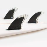 FCS II Reactor Tri Fins - PC Carbon + AirCore: reactor carbon thruster set installed on a white surfboard