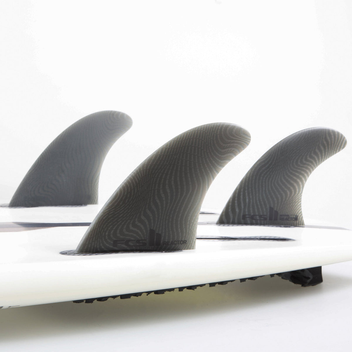 FCS II Reactor Tri Fins - Eco Neo Glass: three Ash fins mounted on a white board in the studio