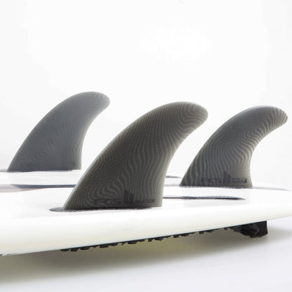 FCS II Reactor Tri Fins - Eco Neo Glass: three Ash fins mounted on a white board in the studio