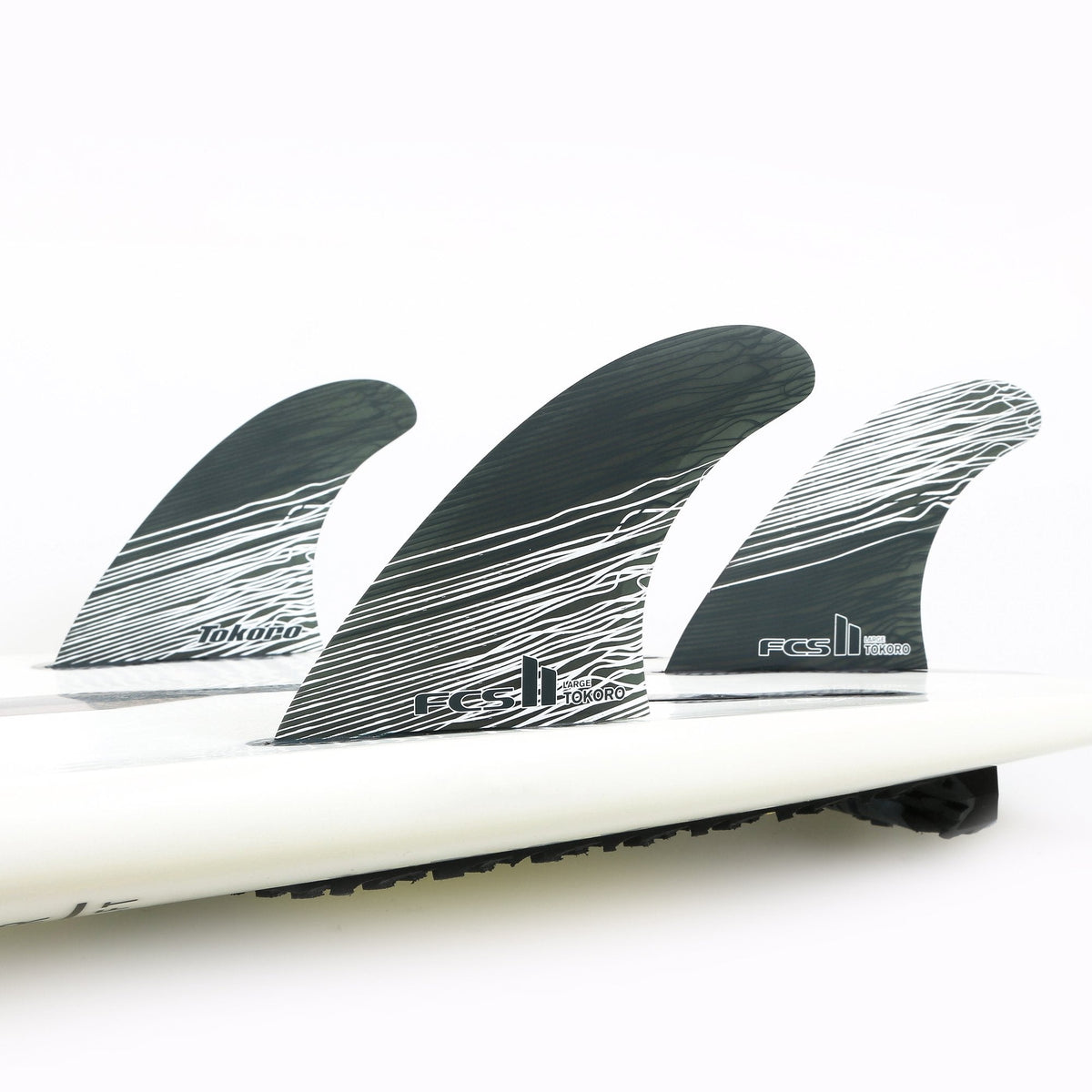 FCS II Tokoro Tri Fins - Performance Core: three Tokoro fins installed on a white board