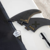 Album fin set, fin key and packaging arranged on a white surfboard