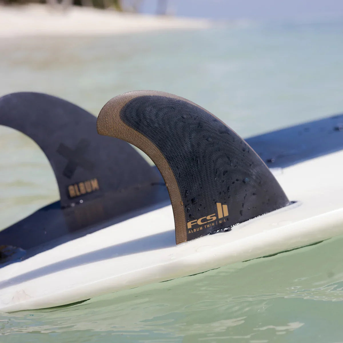 Album twin fins and stabiliser mounted on a surfboard at the water surface