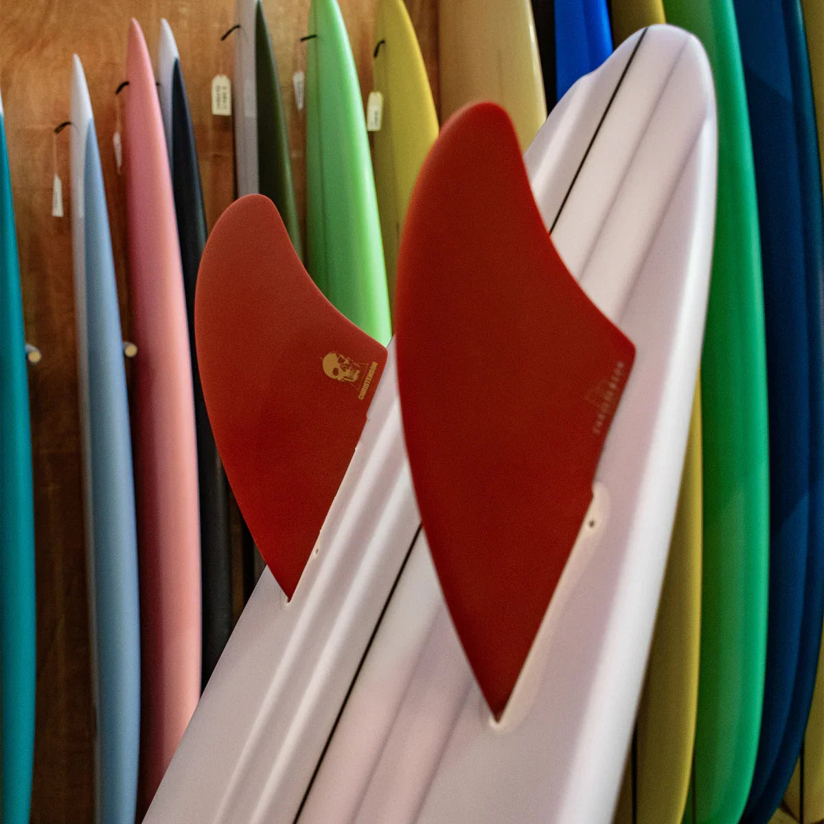 FCS II Christenson Keel - Performance Glass: blood Red keel fins on a board in a surfboard rack