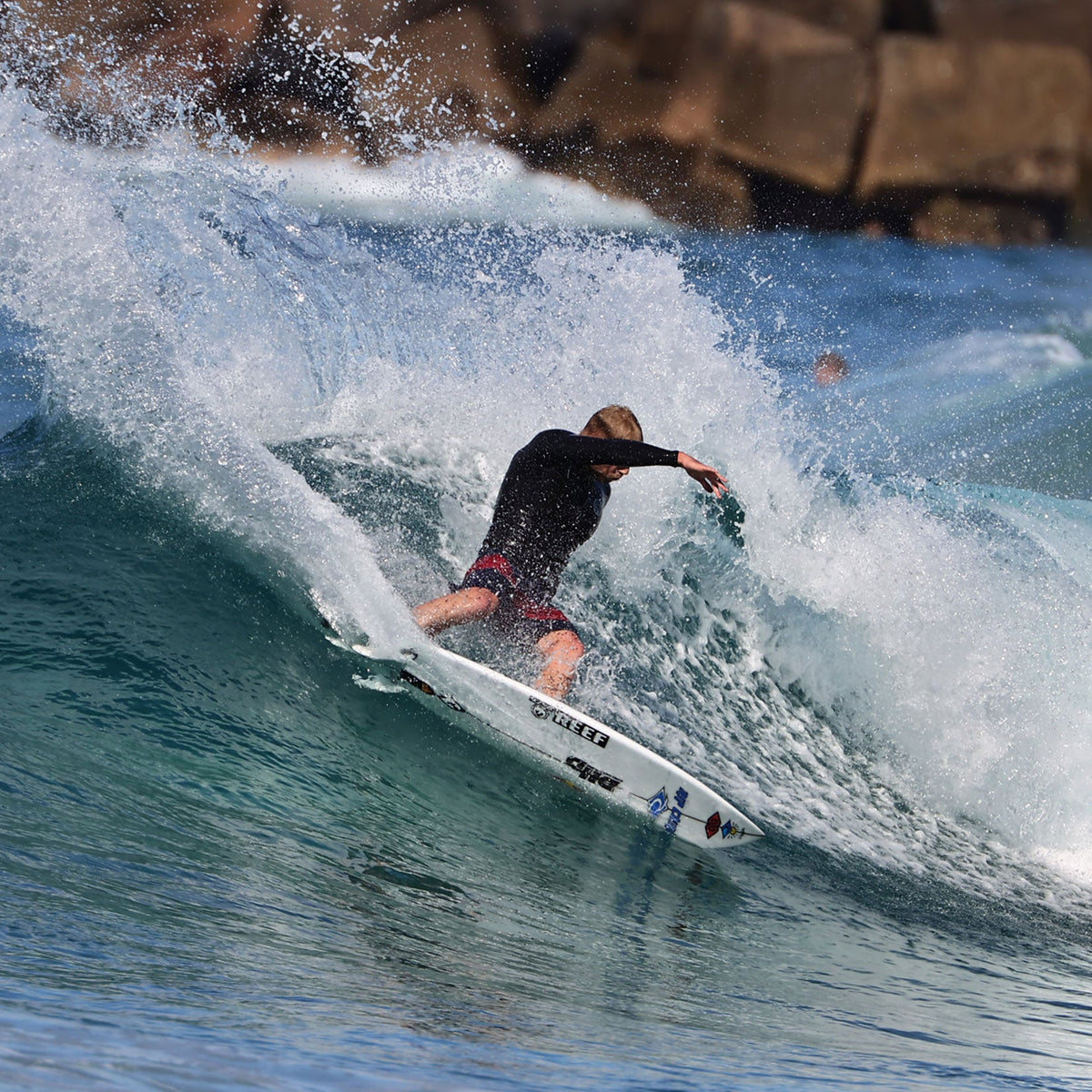 FCS II Mick Fanning Twin + Stabiliser Fins - PC + AirCore: surfer driving through a powerful turn