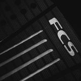FCS Julian Wilson Treadlite Traction: angled view of the centre arch channels beside the FCS logo