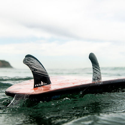 FCS II Tokoro Tri Fins - Performance Core: tokoro fins visible on a surfboard in the sea