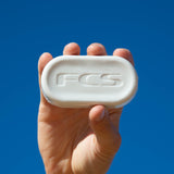 FCS Surf Wax: hand holding a shaped wax bar