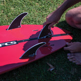 FCS II Harley Longboard Tri Fins - Performance Core: harley fins being installed in a red longboard