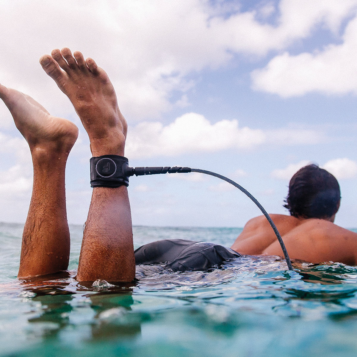 FCS Freedom Helix Leash - Comp 6 ft: surfer floating with an ankle leash above the water