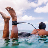 FCS Freedom Helix Leash - Comp 6 ft: surfer floating with an ankle leash above the water