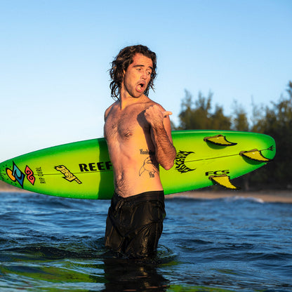 FCS II Mason Ho Tri Fins - PC + AirCore: mason Ho standing in the water with a bright green surfboard