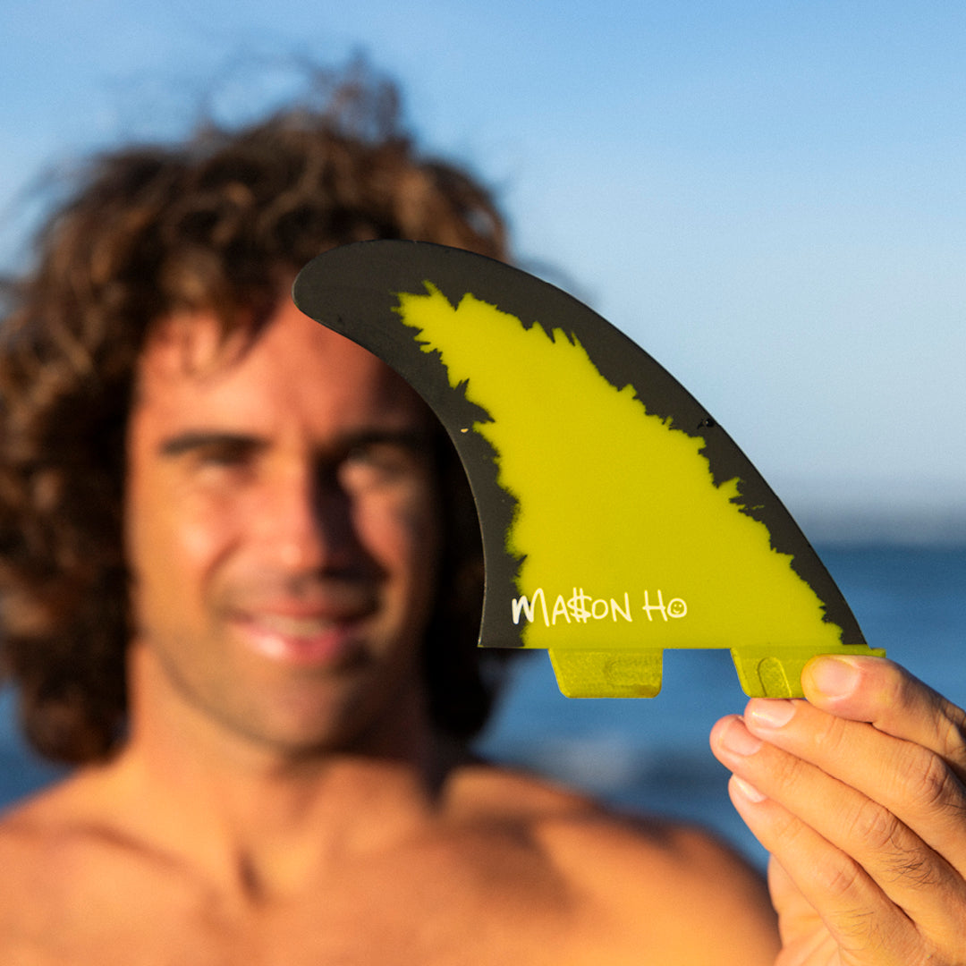 FCS II Mason Ho Tri Fins - PC + AirCore: mason Ho holding his yellow signature fin close to the camera