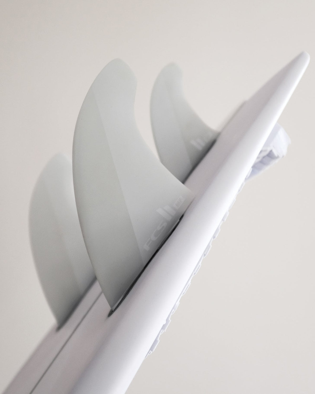 FCS II Mick Fanning Twin + Stabiliser Fins - PC + AirCore: oblique view along a board showing the white twin setup