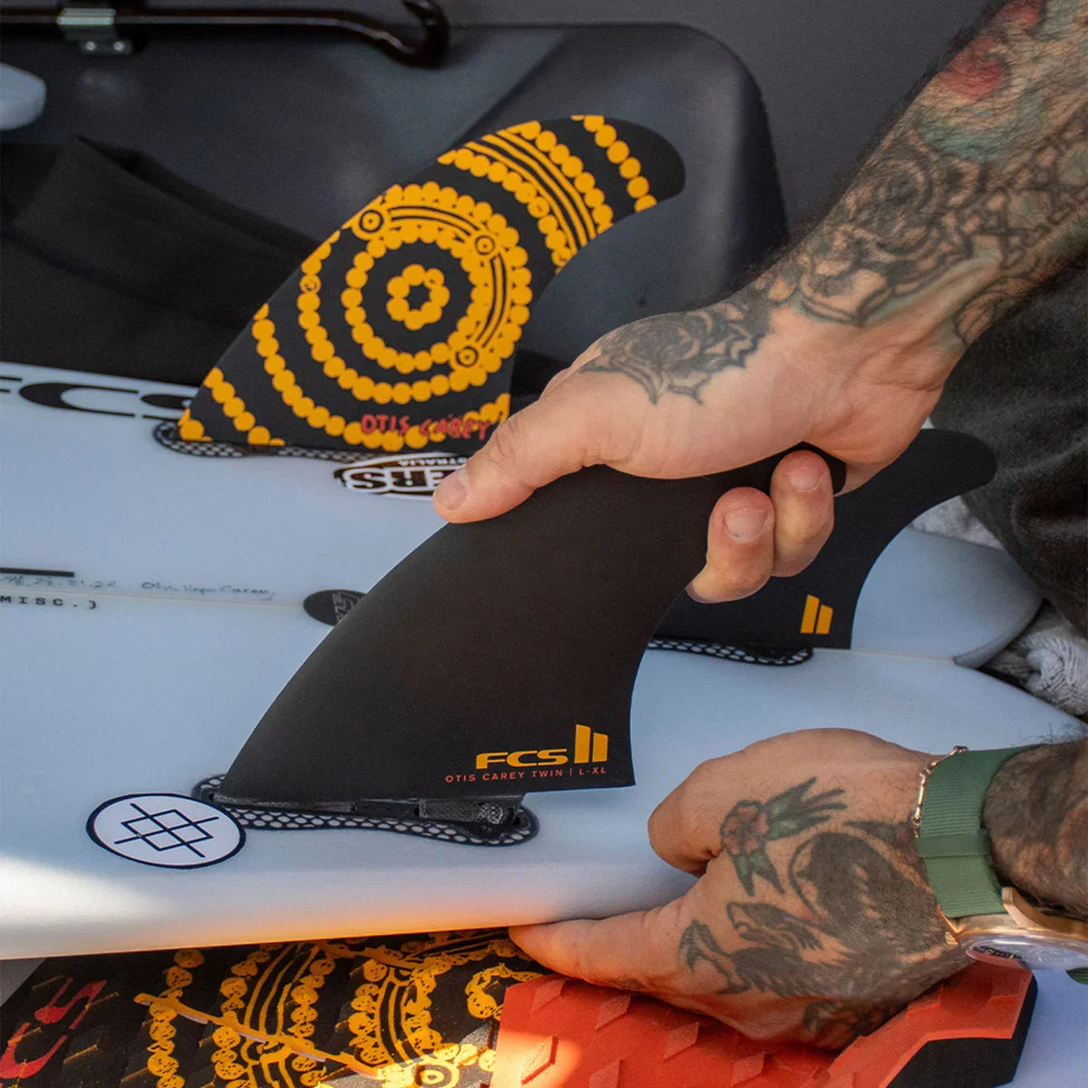 FCS II Otis Carey Twin + Stabiliser Fins - Performance Glass: hands showing the stabiliser beside the patterned twin fin