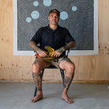 FCS II Otis Carey Twin + Stabiliser Fins - Performance Glass: otis Carey seated beneath his circular artwork