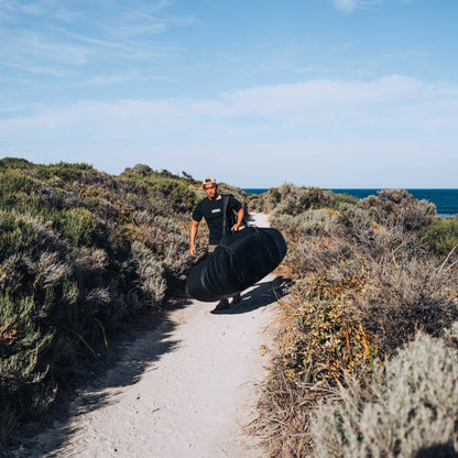 Ocean & Earth APEX Shortboard Travel Cover – 3 Board: APEX cover carried along a coastal path