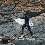 Ocean & Earth Free Flex Gloves – 2 mm: Surfer wearing gloves on a rocky shoreline