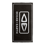Ocean & Earth Priority Beach Towel: Black logo towel laid flat vertically