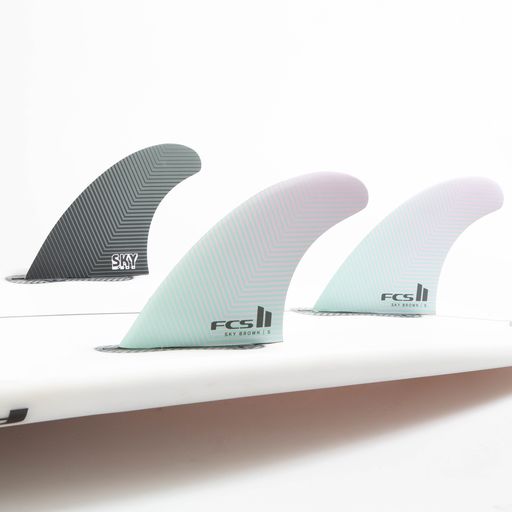FCS II Sky Brown Tri Fins - Performance Core: seafoam and Lavender thruster fins installed on a white board