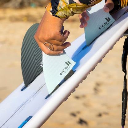FCS II Sky Brown Tri Fins - Performance Core: close view of Sky fitting a fin to a white surfboard
