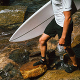 FCS SP2 Reef Boots: surfer wearing SP2 boots on a rocky shore